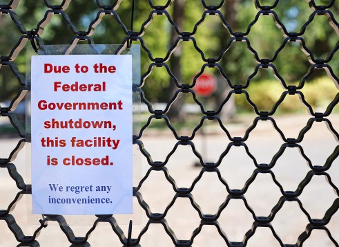 A sign posted on a fence that says, “Due to the Federal Government shutdown, this facility is closed. We regret any inconvenience.”
